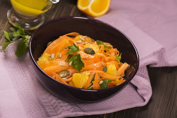Salad with fresh carrot, orange slices, pumpkin and  sunflower seeds. Selective focus