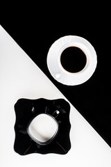 Top view of black and white coffee cups with plates on white and black background
