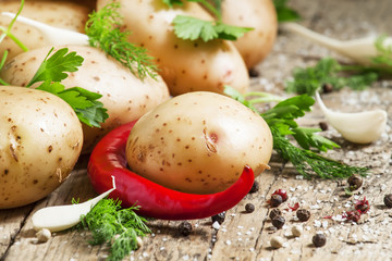 Fresh spring potatoes with spices on the old wooden background i