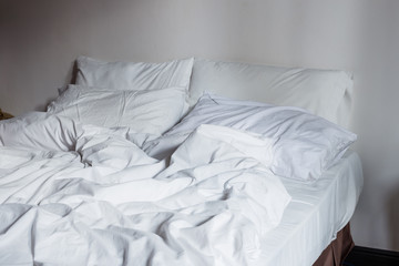 Fototapeta na wymiar White bedding sheets and pillow, Messy bed concept
