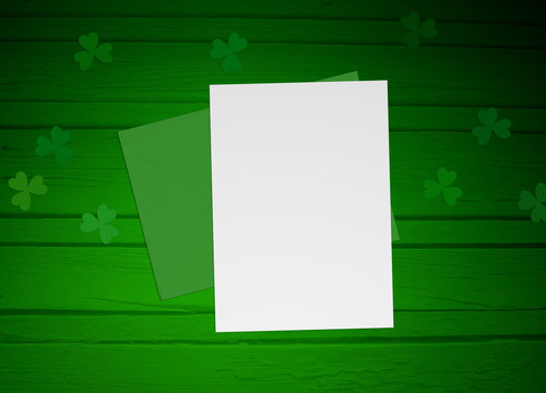 St. Patricks day mock up scene with envelope, blank paper, wooden background and clover leaves