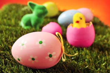 decorated eggs, easter rabbit and toy chick on the grass