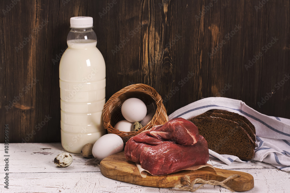 Wall mural Assortment of farmer products over wooden background: milk, eggs, meat and bread. Selective focus