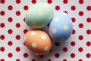 Three colored Easter eggs on patterned background