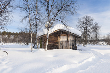 Fototapeta na wymiar Wooden Building On Snow Covered Field