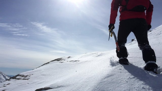 Mountaineer climbing a snowy peak in winter season. Concepts: determination, courage, effort, self-realization. 4KUHD