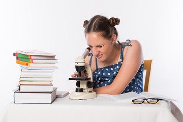 A girl is a teenager looking through a microscope. A study of school subjects. Science and education. School. Exam Preparation.