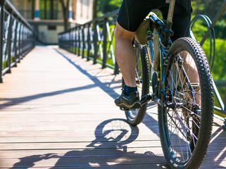 Bicyclist rides on the road in city park. Sunny summer hot day