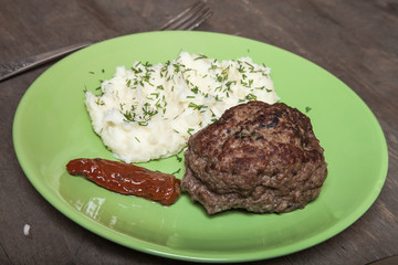 Homemade cutlet with mashed potatoes on a plate on old wooden ta
