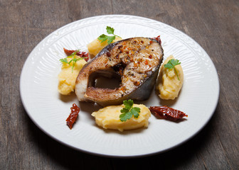 Fried tuna fish with mashed potato, dried tomato and parsley on