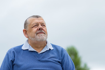 Obraz premium Outdoor portrait of a bearded senior man looking up with hope