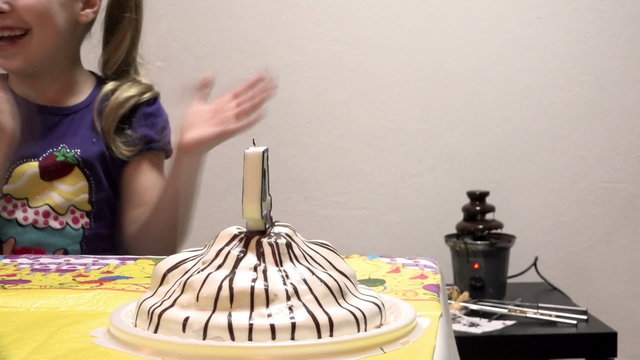 Girl blows out a candle on a birthday cake in honor of his birthday