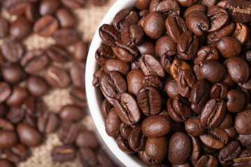 Cup, saucer and coffee beans on a burlap background. Shallow dep