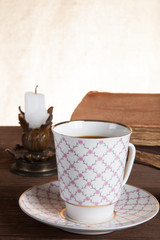 Old books, cup of coffee, candy and ancient candle on the table.
