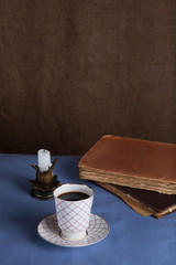 Old books, cup of coffee, candy and ancient candle on the table.