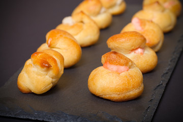 Set of small profiteroles on a black slate plate. Shallow depth
