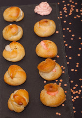 Set of small profiteroles on a black slate plate. Selective focu