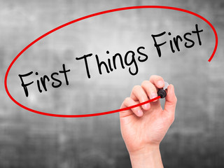 Man Hand writing First Things First with black marker on visual