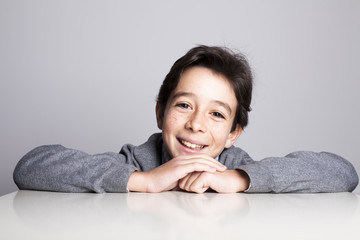 Niño sonriendo apoyado sobre la mesa