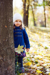 Cute little girl peeking from behind a tree.