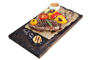 Ribeye steak on parchment paper and board from burnt wood.