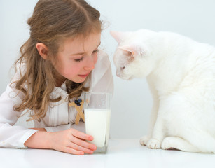Little girl share glass of milk with cat.