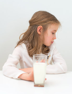 Sad little girl with glass of milk.