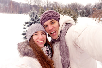 Happy couple doing selfie on a date in park in winter