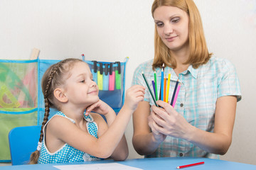 The five-year child picks a pencil in the hands of mother
