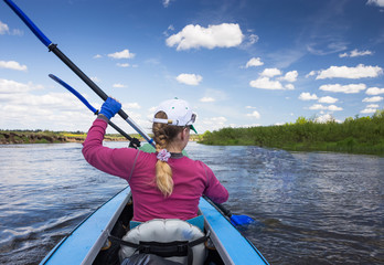 Young people are kayaking on a river in beautiful nature. Summer sunny day