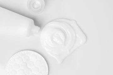 splash of white cream, tube and cosmetic cotton disk