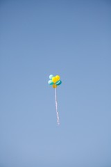 Bright colorful inflatable balloons up in air over blue sky background.