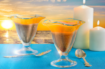 Glasses with dessert and candles at sunset