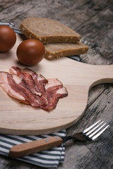 Kitchen cutting board with food ingredients photographed from a side on old rustic wooden table.