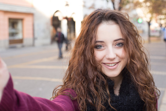 happy teen girl doing selfie photo on street in autumn