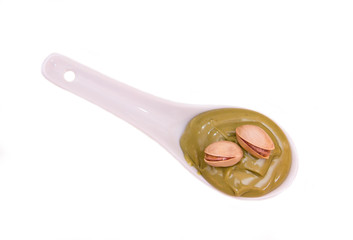 Pistachio cream on spoon on white background view from above
