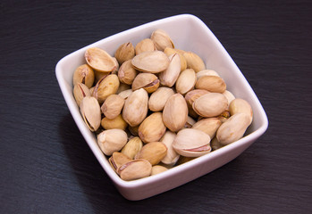 Pistachios on a square bowl on slate top