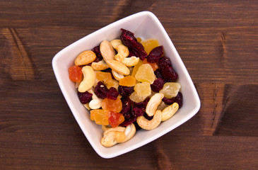 Dried fruits on a square bowl on wooden table seen from above