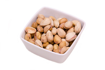 Square bowl of pistachios on white background
