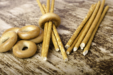 Pile of bagels and sweet sticks on brown background.