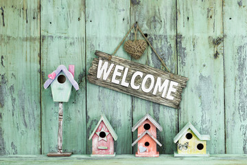 Welcome sign hanging over row of colorful spring birdhouses