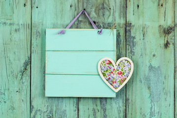 Blank mint green sign with fabric heart hanging on rustic background