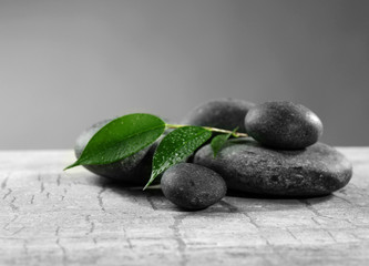 Composition of pebbles with leaf on the table against grey background
