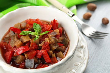 Ratatouille in bowl, on wooden table background