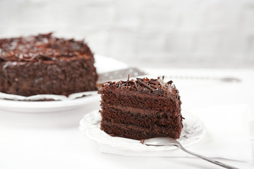 Sliced chocolate cake on wooden table, on light background