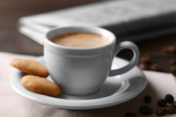 Cup of coffee, cookie and newspaper on wooden table background