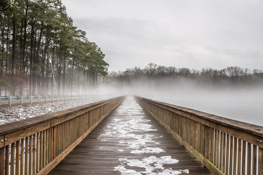 Fototapeta Stumpy Lake fishing pier in snow, ice and fog in Virginia Beach, Virginia. 