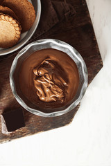 Melted chocolate in bowl, on wooden background