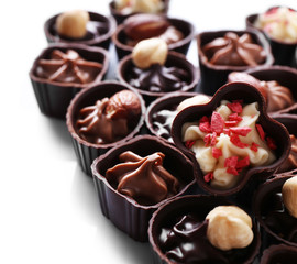 Delicious chocolate candies on white background, close up