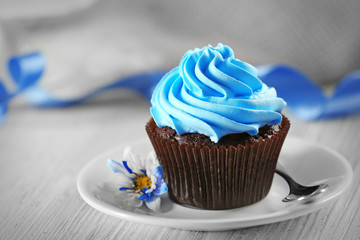 Delicious chocolate cupcake with blue cream on decorated wooden  table, close up
